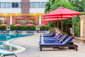 a row of lounge chairs with umbrellas next to a pool at Mountain Beach Resort in Pattaya South
