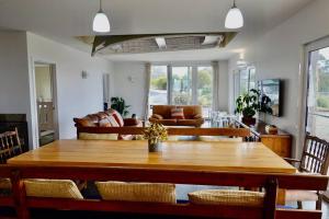 - un salon avec une table et des chaises en bois dans l'établissement Waterfront 'Jemadda' Family Lodge, à Bream Creek