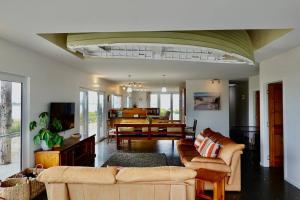 a living room with couches and a dining room at Waterfront 'Jemadda' Family Lodge in Bream Creek