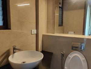 uma casa de banho com um lavatório branco e um espelho. em Tara Suites Premium rooms in Central Indiranagar em Bangalore