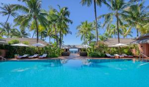 a swimming pool at a resort with palm trees at Bayview - The Beach Resort in Ngapali