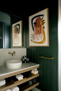 ein Badezimmer mit einem Waschbecken und zwei gerahmten Bildern in der Unterkunft Cupitt's Estate Villas in Ulladulla