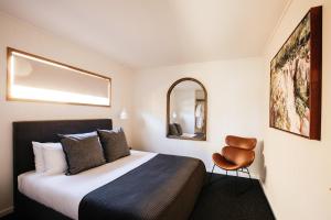 a hotel room with a bed and a chair at Cupitt's Estate Villas in Ulladulla