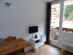 uma sala de estar com uma mesa e uma televisão na parede em Studio Valfréjus, 1 pièce, 3 personnes - FR-1-561-52 em Valfréjus