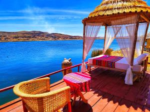 - un kiosque avec un lit, une table et des chaises sur une terrasse dans l'établissement Uros Qhantany Lodge, à Puno