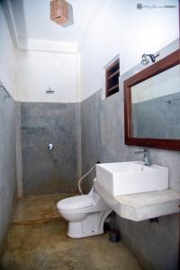 ein Badezimmer mit einem Waschbecken, einem WC und einem Spiegel in der Unterkunft ohm lagoon home in Tangalle