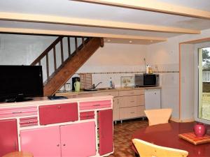 uma cozinha com armários cor-de-rosa e uma mesa com televisão em Maison Trébeurden, 3 pièces, 5 personnes - FR-1-368-71 em Trébeurden