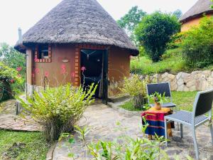 a small hut with a thatched roof and a table and chairs at Nyore Hillside Retreat in Mbarara