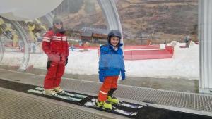 two children standing on a ski lift in the snow at Le Peyroutet in Cazaux-Villecomtal