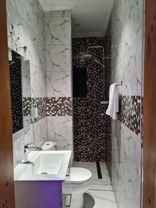 een badkamer met een witte wastafel en een toilet bij FIRST RESIDENCE KRIBI in Kribi