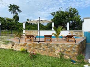 a patio with two benches and an umbrella at FIRST RESIDENCE KRIBI in Kribi