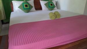 a bed with a pink and green blanket on it at Wild View Stay in Habarana