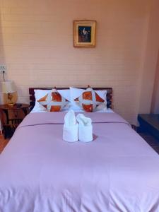 uma cama branca com dois sapatos brancos em Bunraksa Resort em Kamphaeng Phet