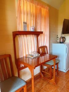 einen Holztisch und Stühle mit einem Tisch und einem Kühlschrank in der Unterkunft Bunraksa Resort in Kamphaeng Phet