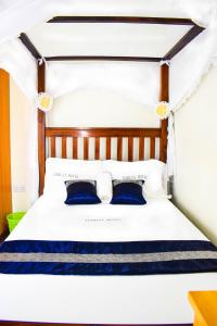 a bedroom with a white bed with blue pillows at Dahlia Hotel and Accommodation in Homa Bay
