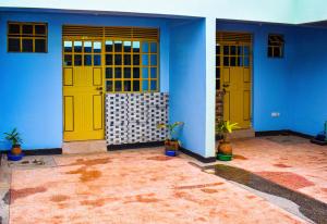 a blue building with yellow doors and potted plants at Dahlia Hotel and Accommodation in Homa Bay