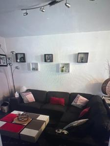 un soggiorno con divano nero e quadri alle pareti di lily's rooms a Mulsanne