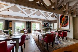 a dining room with tables and red chairs at Migdash Guesthouse in Hartbeespoort