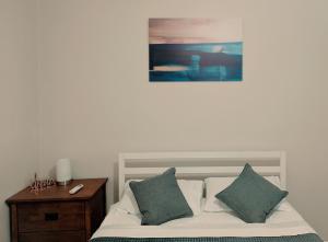 un letto con due cuscini e un quadro sul muro di Broken Hill Inn Cottage a Broken Hill