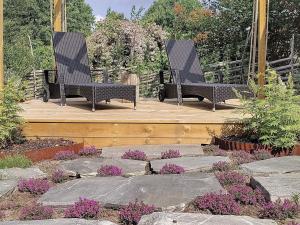 dos bancos sentados en una terraza de madera con flores en 8 person holiday home in VAXHOLM en Rindö