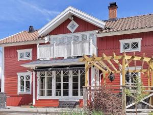 Rindö的住宿－8 person holiday home in VAXHOLM，红色的房子,设有白色门廊和阳台