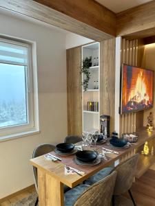 a dining room with a table with chairs and a fireplace at Pinewood apartment Jahorina in Jahorina