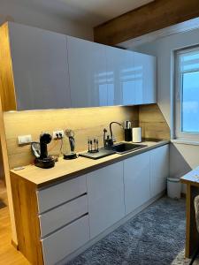 a kitchen with white cabinets and a sink at Pinewood apartment Jahorina in Jahorina