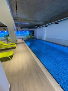 een groot zwembad in een gebouw met gele stoelen bij Villa Residence Apartment in Tbilisi City