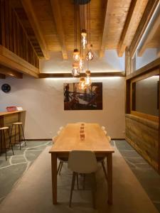 une salle à manger avec une table en bois et un lustre dans l'établissement Duplex Spa Access in front of skislope by Jolidi, à Nendaz