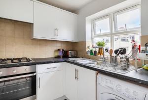 a kitchen with white cabinets and a sink at White House in Bournemouth