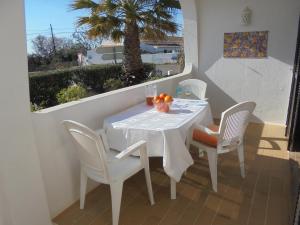 een witte tafel en stoelen op een balkon met een palmboom bij Apartamento Neptuno in Benagil