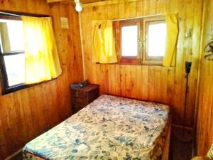1 dormitorio pequeño con 1 cama y 2 ventanas en Cabaña del humedal en Tigre