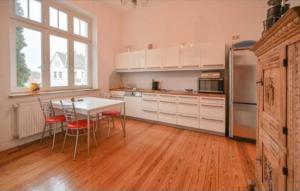 - une cuisine avec des placards blancs, une table et des chaises dans l'établissement Weiße Villa 1, à Duderstadt