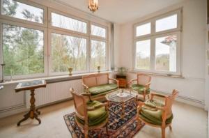 - un salon avec des chaises, une table et des fenêtres dans l'établissement Weiße Villa 1, à Duderstadt