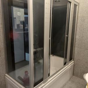 una ducha de cristal en un baño con lavabo en Roxana apartament 3 camere, en Râmnicu Vâlcea