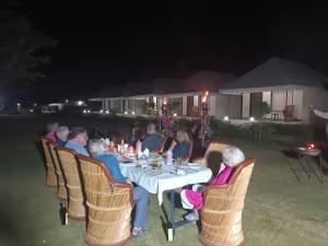 Un groupe de personnes assises autour d'une table la nuit dans l'établissement Vacation Village Camps - A Unit Of Nature Resort, à Pushkar