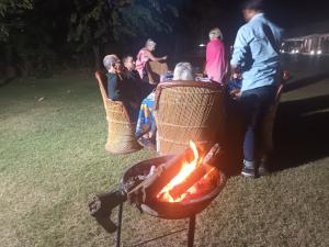 a group of people sitting around a grill at night at Vacation Village Camps - A Unit Of Braham Vatika Resort in Pushkar