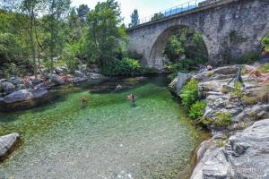 a group of people swimming in a river under a bridge at Studio Venaco Centre Corse in Venaco