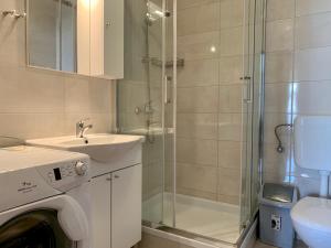 a bathroom with a shower and a sink and a washing machine at Feniks Apartmani Lopar in Lopar +41 photos
