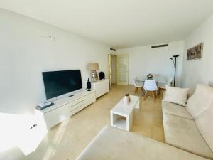 sala de estar con sofá blanco y TV en Akira Flats Diagonal Mar Apartments en Barcelona