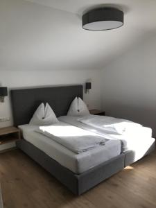 a bedroom with a large bed with white sheets at Pension Pichler in Sillian