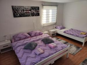 a bedroom with two beds with purple sheets and pillows at Kuća Vila Nina in Tomislavgrad