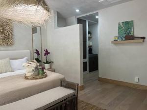 a bedroom with a bed with a bench and a chandelier at Tiki Tiki - Gorgeous Boho Beach Hideaway! in Wailea