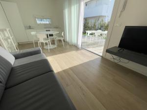 a living room with a couch and a table with chairs at JESOLO GROUND FLOOR FLAT WITH POOL - 2 family apartments in Lido di Jesolo