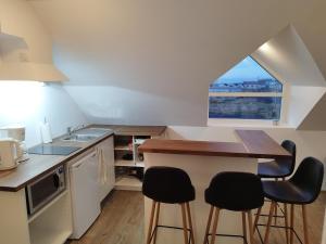 a kitchen with a counter with stools and a window at Guesthouse Háteigi in Þykkvibær