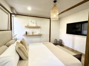 um quarto com uma cama branca e uma luz pendente em Aloha Moon - A Chic and Dreamy Modern Tropical Hideaway! em Wailea
