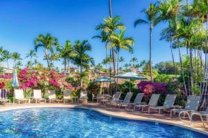 einen Pool in einem Resort mit Stühlen und Palmen in der Unterkunft Aloha Moon - A Chic and Dreamy Modern Tropical Hideaway! in Wailea