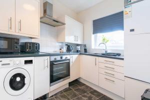 cocina con armarios blancos, lavadora y secadora en Stylish & Central 2 bedroom apartment - Fast WiFi en Castle Donington