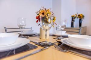 a table with plates and glasses and a vase of flowers at Stylish & Central 2 bedroom apartment - Fast WiFi in Castle Donington