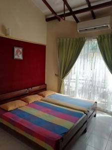 1 dormitorio con cama de arco iris y ventana en McCarthy Guesthouse, en Kandy